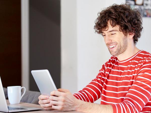 Chico con jersey de rayas delante de un portátil usando una tablet
