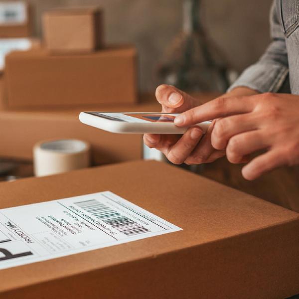 person hovering a phone over a shipping label pasted on a shipping box