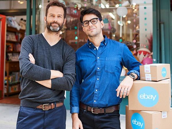 two men next to a pile of eBay boxes