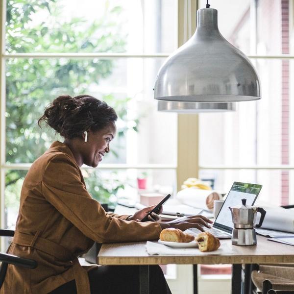 Woman looking at her phone and laptop at a cafe