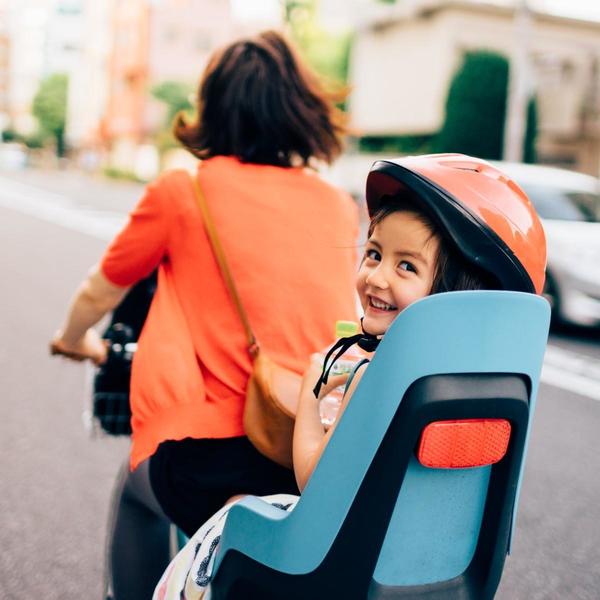 Child on the back of a bike with a helmet smiling at camera