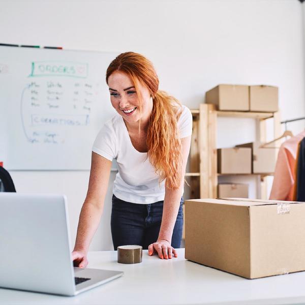 Woman using laptop with package beside her