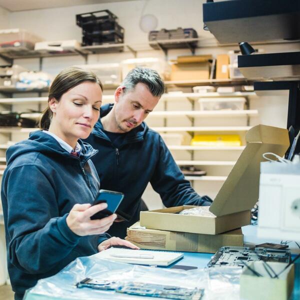 Woman looking at cellphone with a man beside her looking at an open box