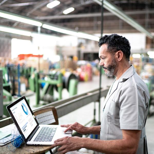 Hombre consultando un gráfico en un portátil en una fábrica