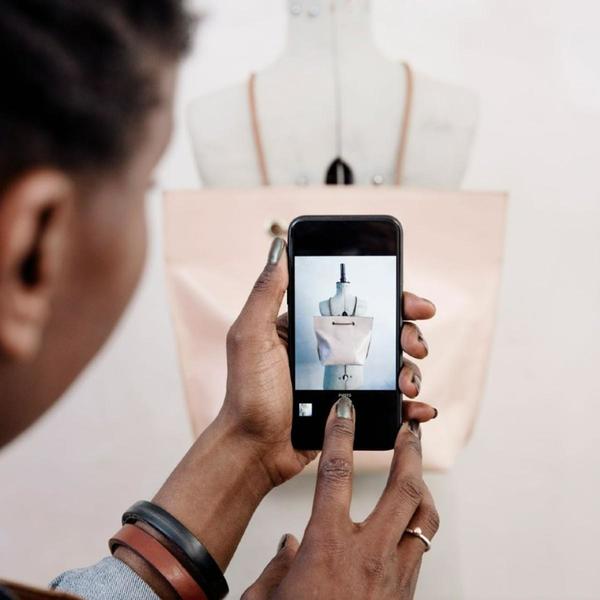 lady using her phone to take a photo of bag hung on a mannequin