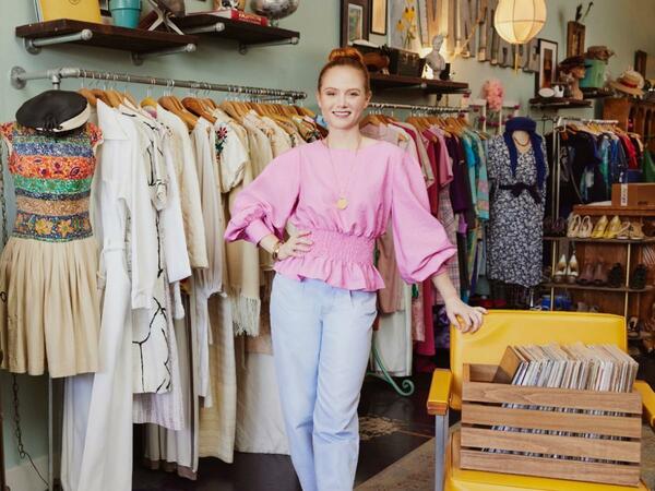 Woman in pink shirt standing in front of clothes rack