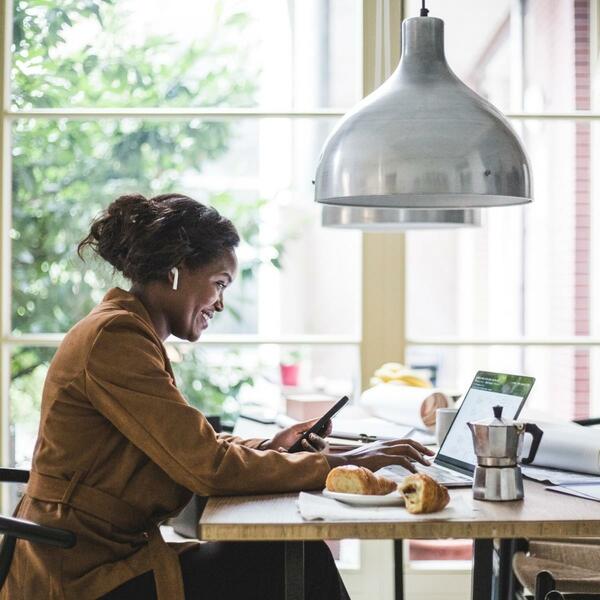 Woman using cellphone and typing on computer at a cafe