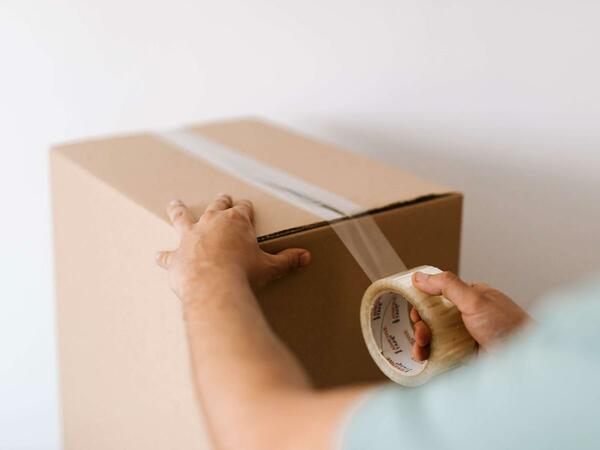 person sealing box with packing tape