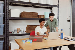 two boys looking at laptop in office with eBay shipping supplies