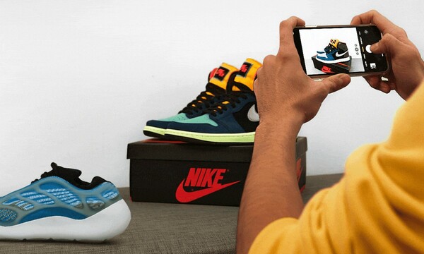 A person uses their cell phone to take a picture of a pair of sneakers