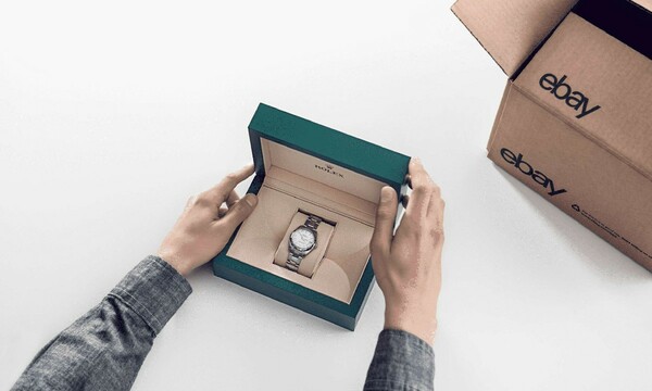 A person holding an open box with a luxury watch inside