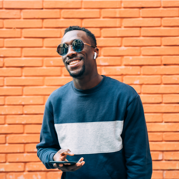 Man with phone and large sunglasses smiling