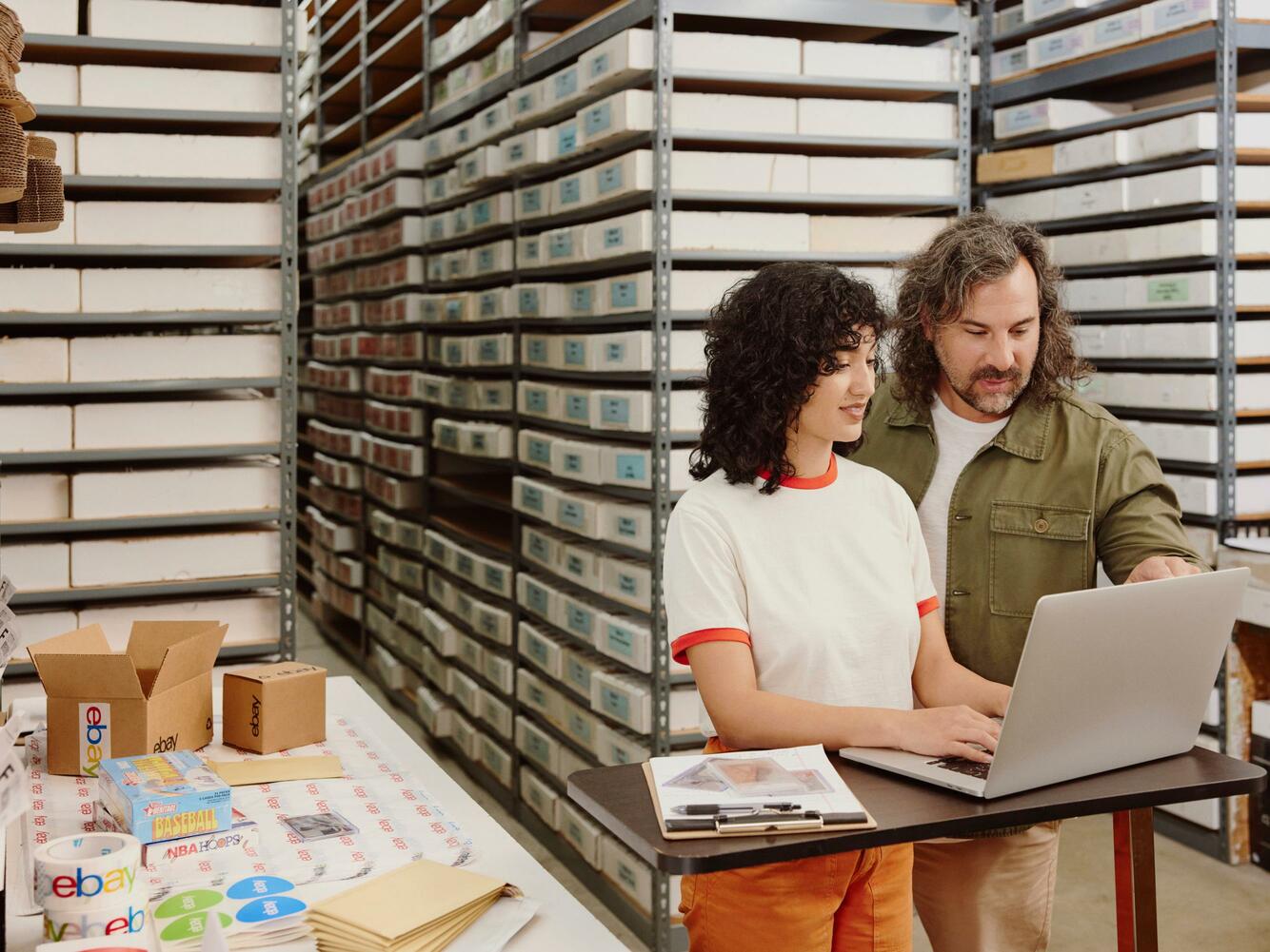 Man and woman looking at laptop in a warehouse setting.
