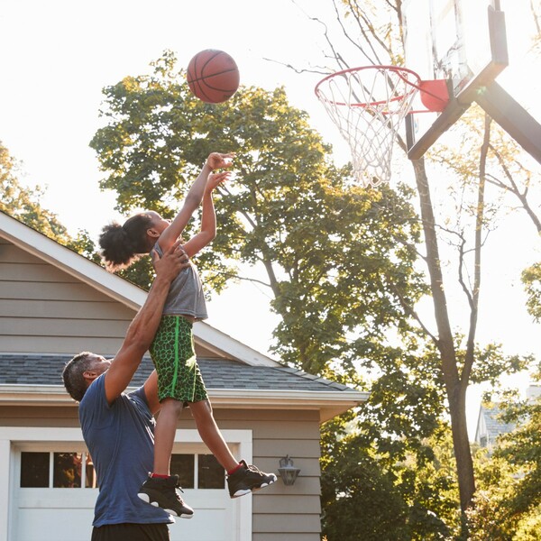 Dad lifting daughter up to shoot a basket