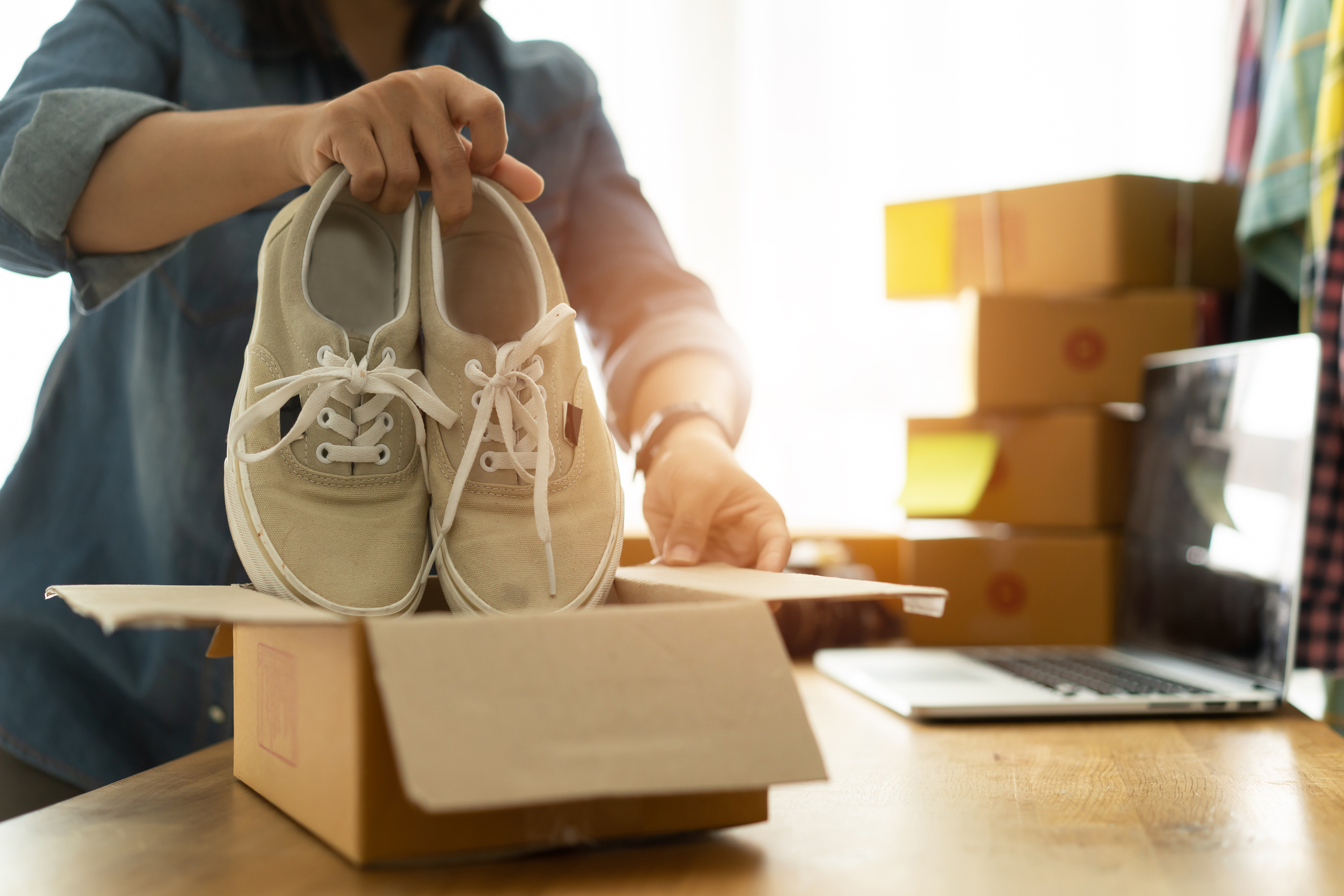 person packing pair of shoes on a box