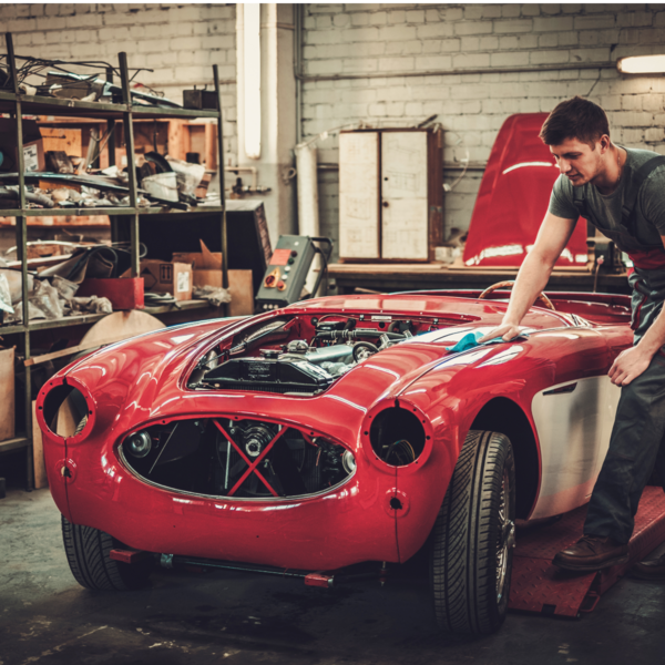 man fixing red car in workshop