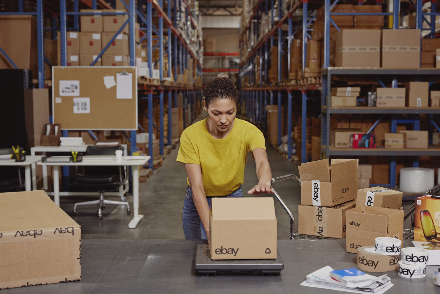 woman wearing yellow shirt packing boxes in warehouse