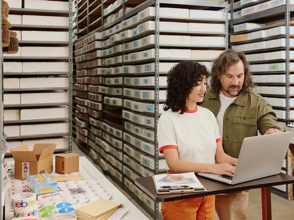 Man and woman looking at laptop in a warehouse setting.