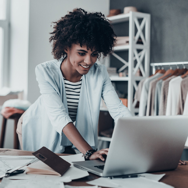 Femme penchée sur un portable avec des papiers éparpillés sur le bureau