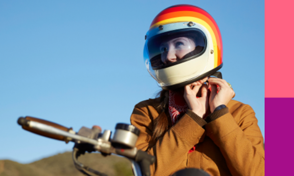 Woman on a motorcycle securing the strap on her helmet.