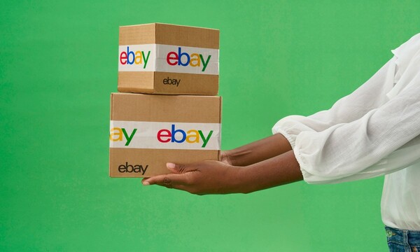 woman holding eBay packages against green background