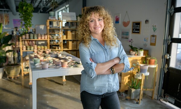 Woman standing with crossed arms in front of her pottery.