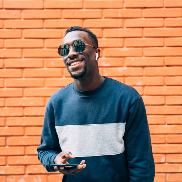 Homme avec un téléphone et de grandes lunettes de soleil qui sourit