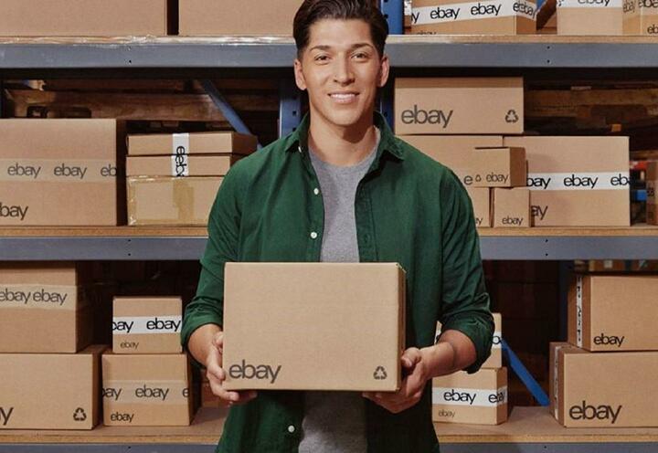 eBay-Verkäufer vor Regal mit eBay-Paketen