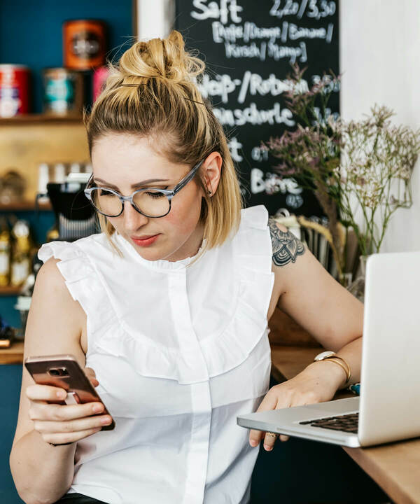 Woman with white blouse and glasses looking at her mobile phone.