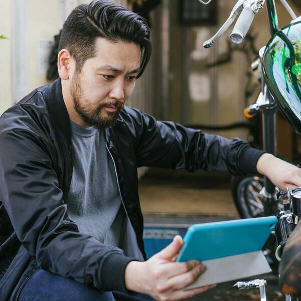 man beside his bike while holding a tablet