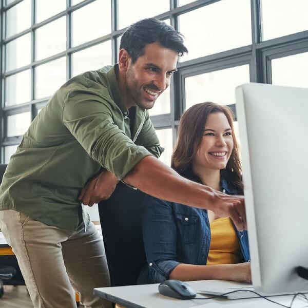 A man and woman in front of desktop