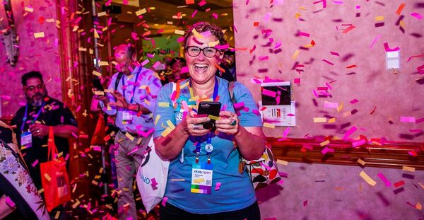 Woman coming out of conference room with others, smiling with confetti around her.