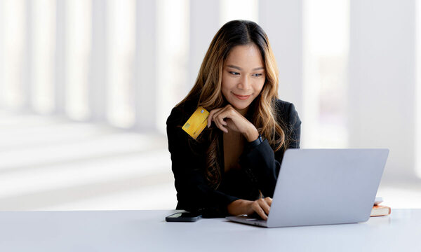 lady holding credit card while looking at laptop