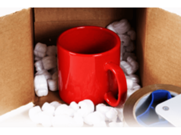 A red mug inside of an open box with styrofoam fillers around it