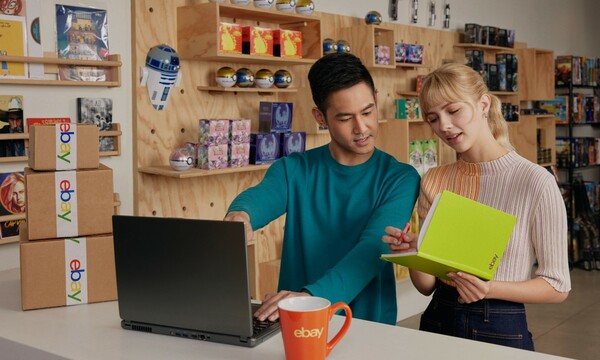 Un homme et une femme qui regardent une carte Pokémon devant un portable dans un magasin de loisirs