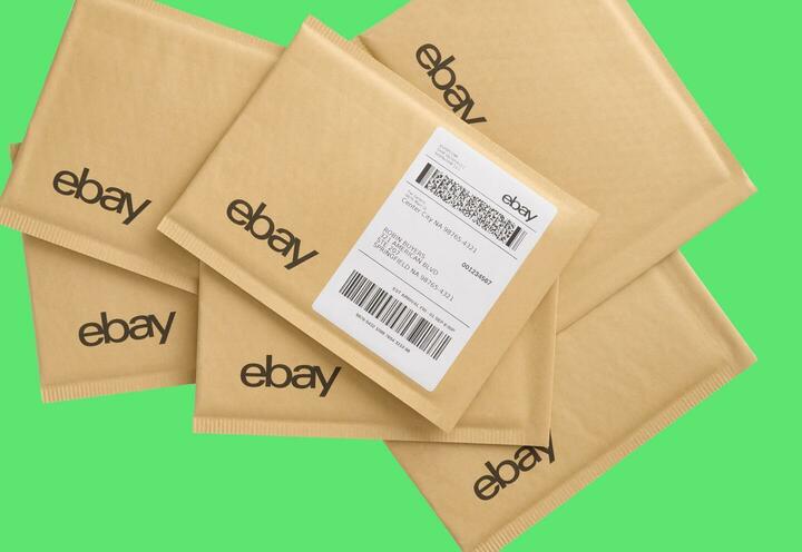 A stack of eBay branded paper mail jackets with an eBay shipping Label applied on a green backdrop.