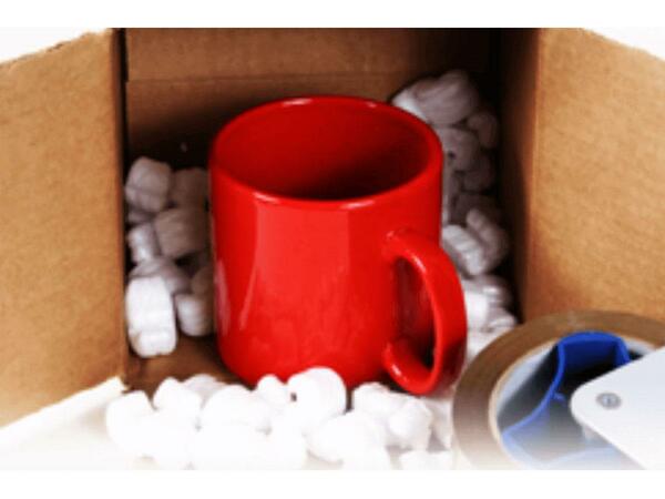 A red mug inside of an open box with styrofoam fillers around it