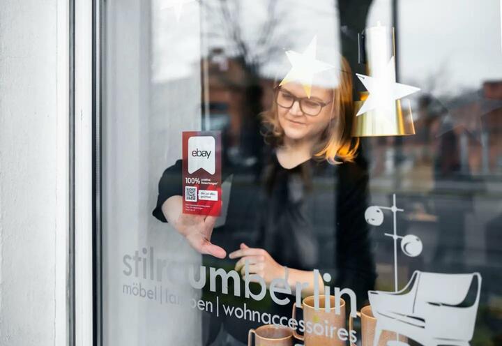 Woman applying shop sticker to her shop window