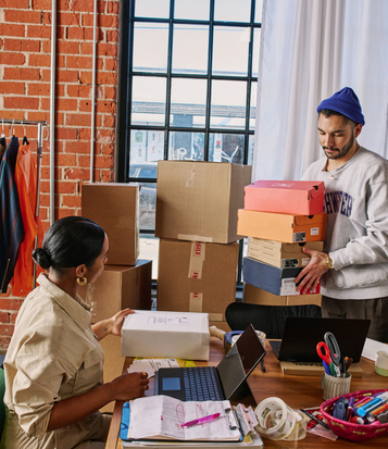 Kolleg*innen packen Pakete im Office