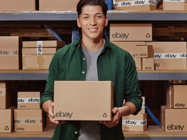 eBay-Verkäufer mit Paket mit eBay-Logo in den Händen