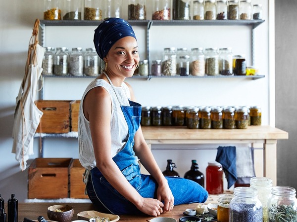 Uśmiechnięta kobieta w stroju roboczym siedząca na blacie w swoim sklepie