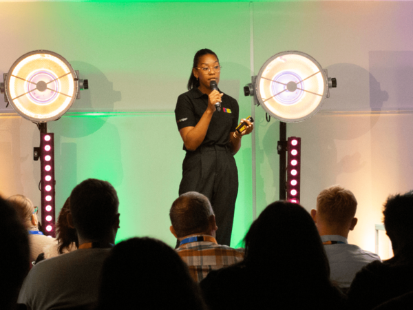 A woman presenting to an audience whilst wearing a black eBay shirt.