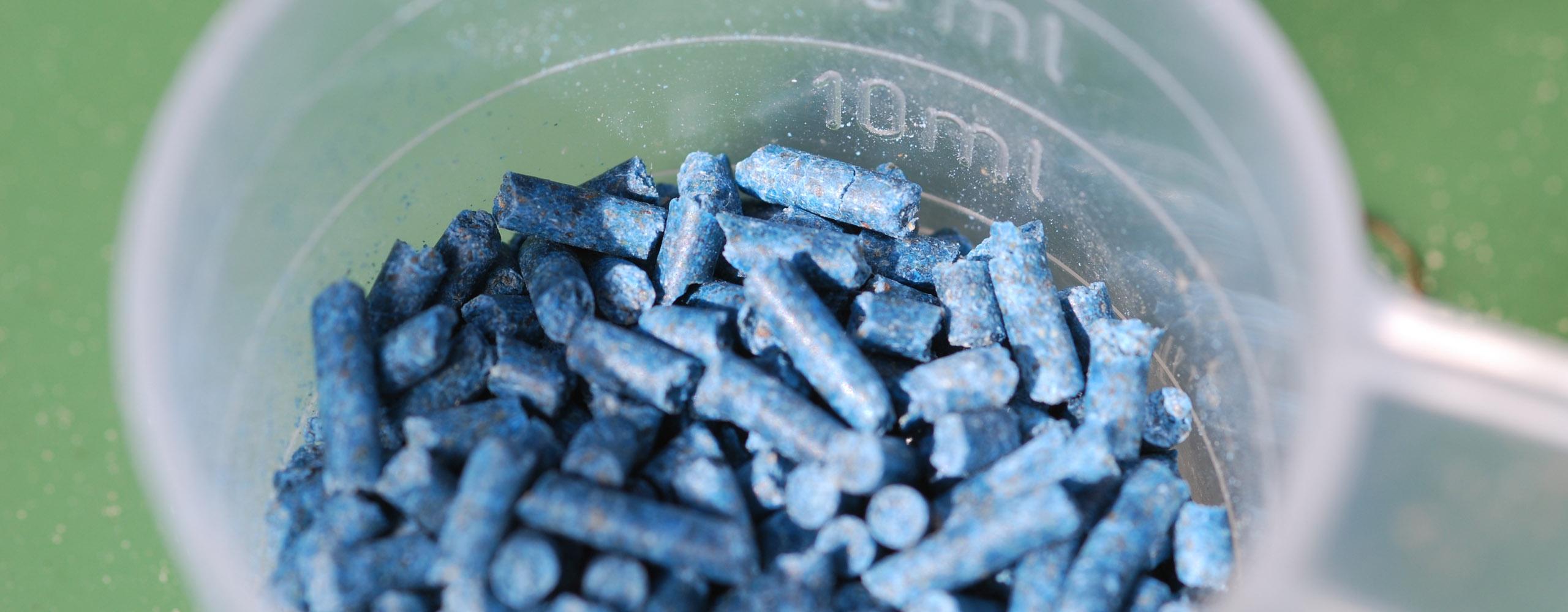 Ein Messbecher ist zu 10 Millilitern mit blauem Granulat gefüllt, dem giftigem Schneckenkorn.