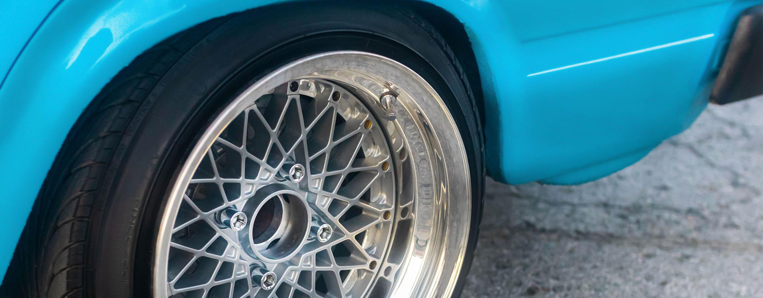 Eine Tiefbettfelge an einem hellblauen Auto in Nahaufnahme