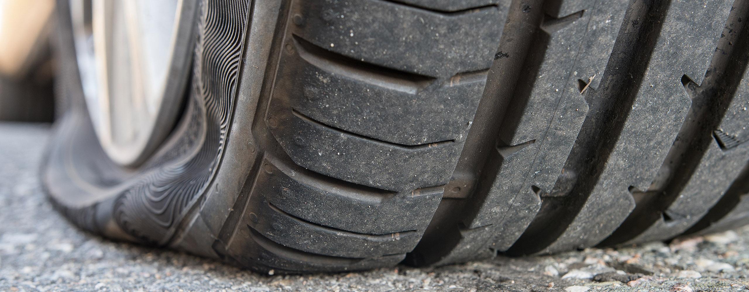 Nahaufnahme eines platten Reifens auf einer Straße.
