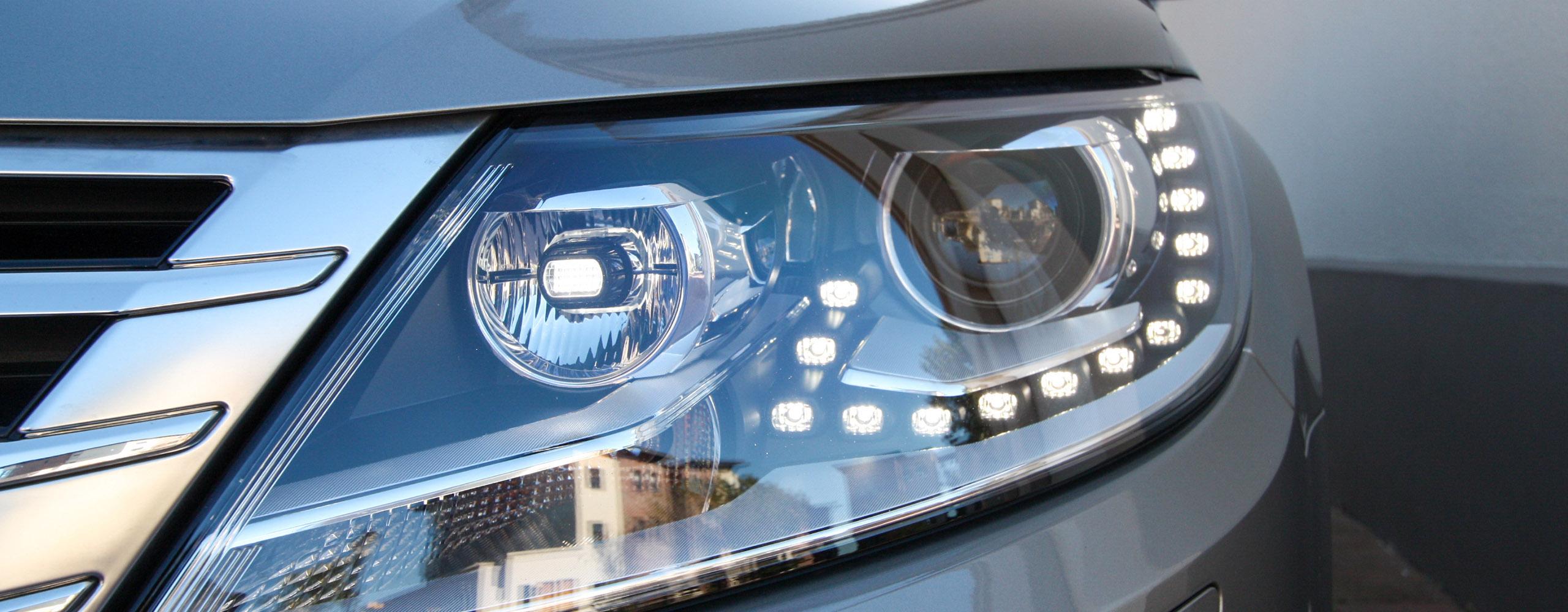 Der linke Scheinwerfer eines grauen PKWs mit eingeschaltetem LED-Tagfahrlicht