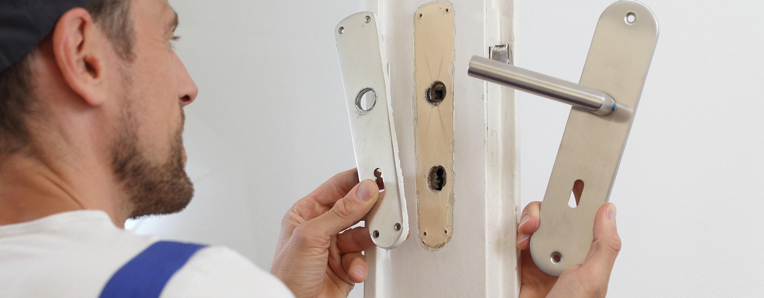 Ein Handwerker tauscht die Türklinke einer Tür aus