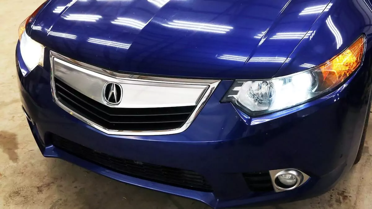 Front end of a blue Acura wagon with a faulty headlight.