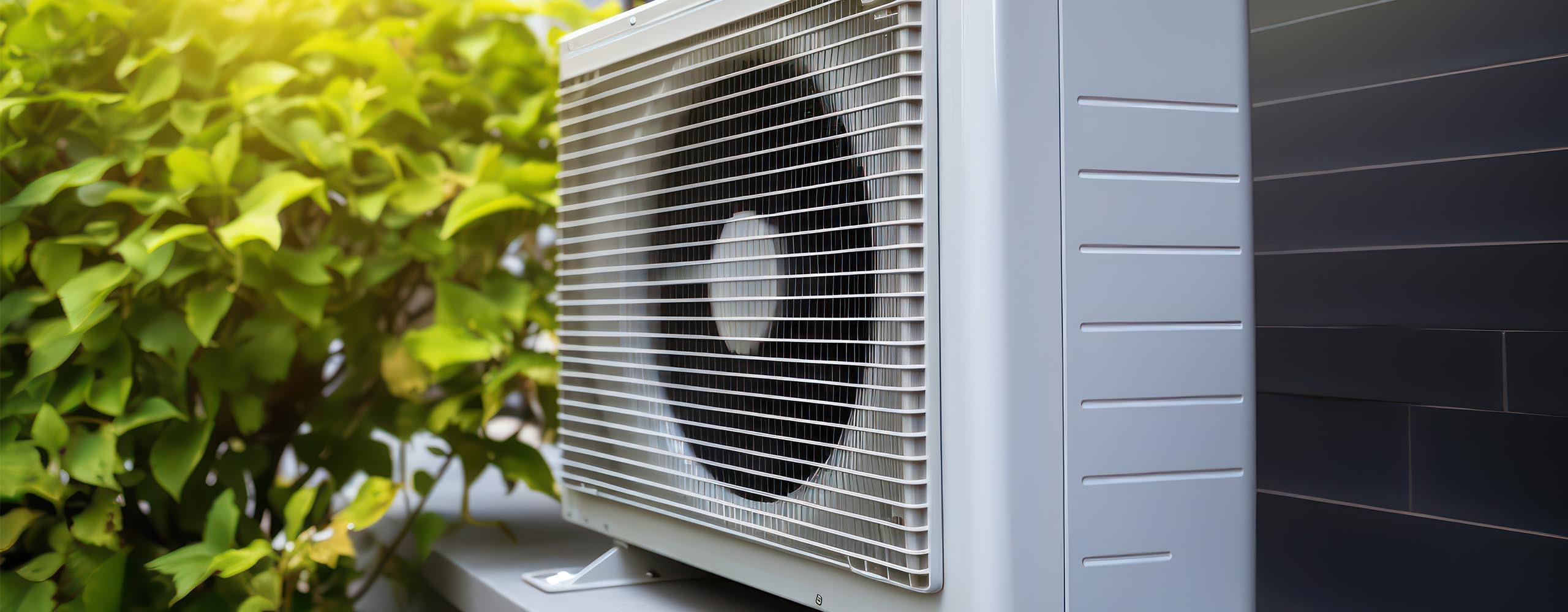 Die Außenkomponente einer Klimaanlage ist vor einer Hauswand positioniert.