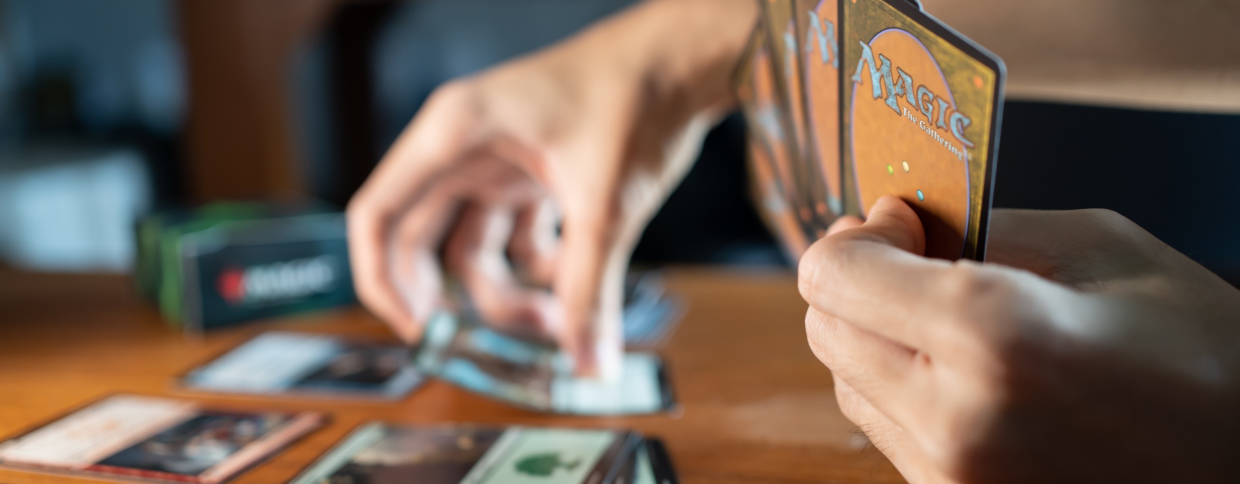 Eine Hand ragt in den linken Bildrand und greift nach Spielkarten.